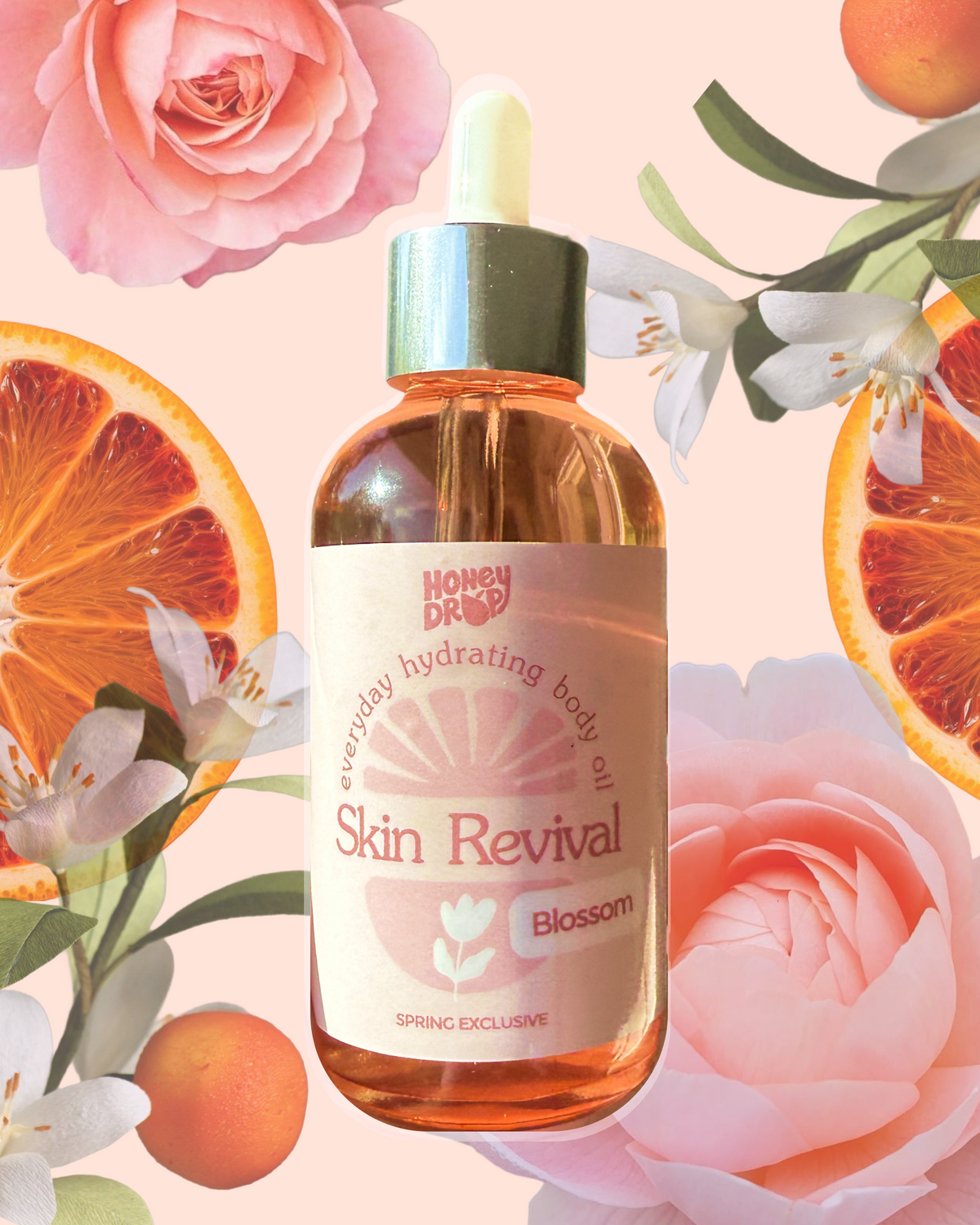A bottle of Honshu Drops Skin Revival Blossom body oil centered against a soft pink floral background with roses, citrus slices, and white blossoms. The bottle is amber glass with pink liquid, a pale green dropper top, and a cream label with pink text.