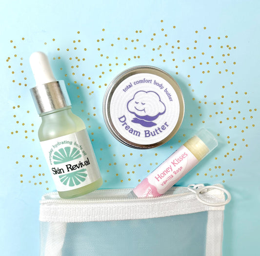A mini trio of HoneyDrop's best selling items, skin revival body oil, dream butter body butter, and honey kisses lip balm packaged in a white mesh pouch