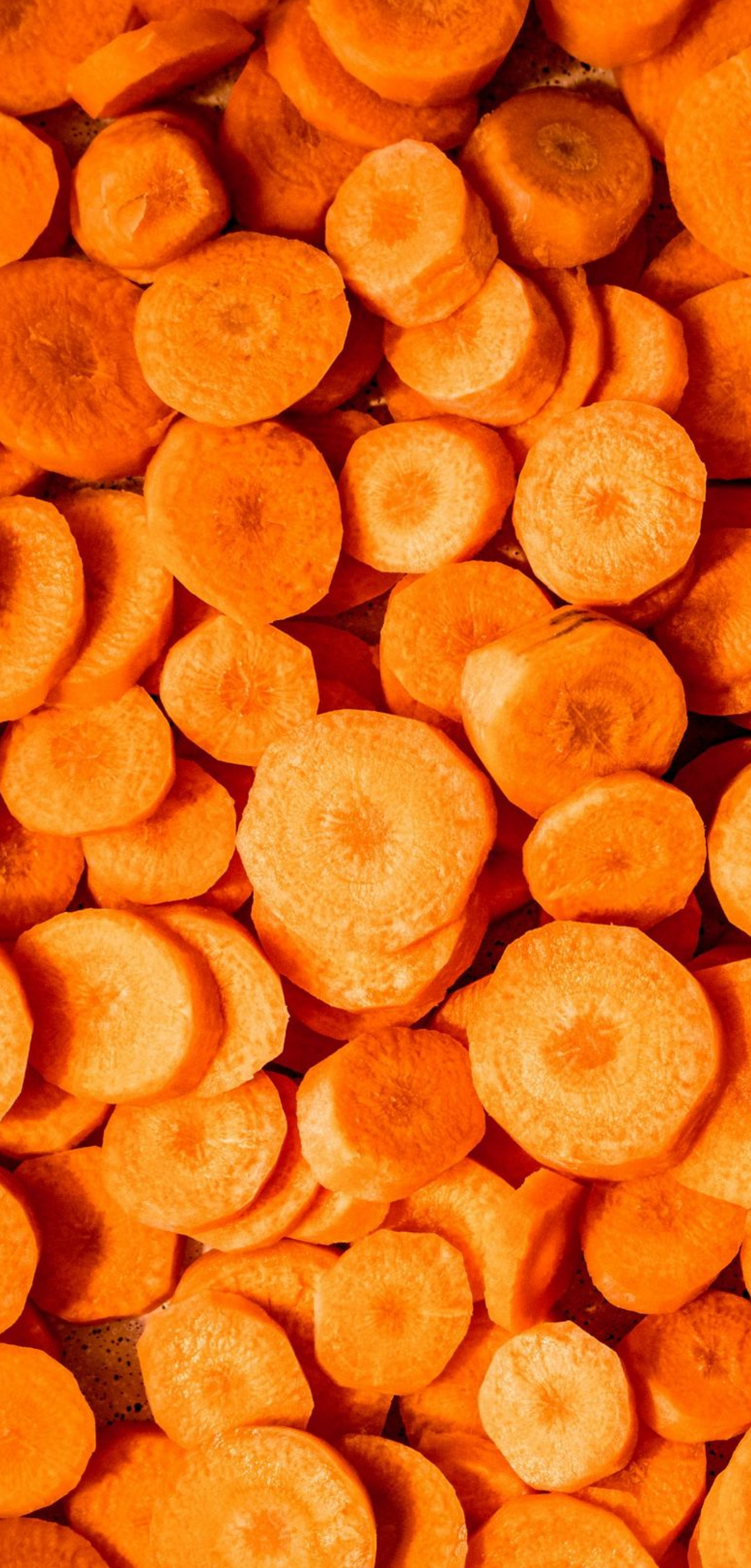 A close-up, top-down view of sliced orange carrots filling the frame, with layered circular cross-sections and visible natural texture.