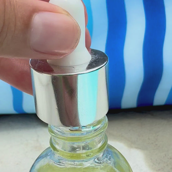 Lightweight skin revival body oil being dispensed from a dropper into the bottle