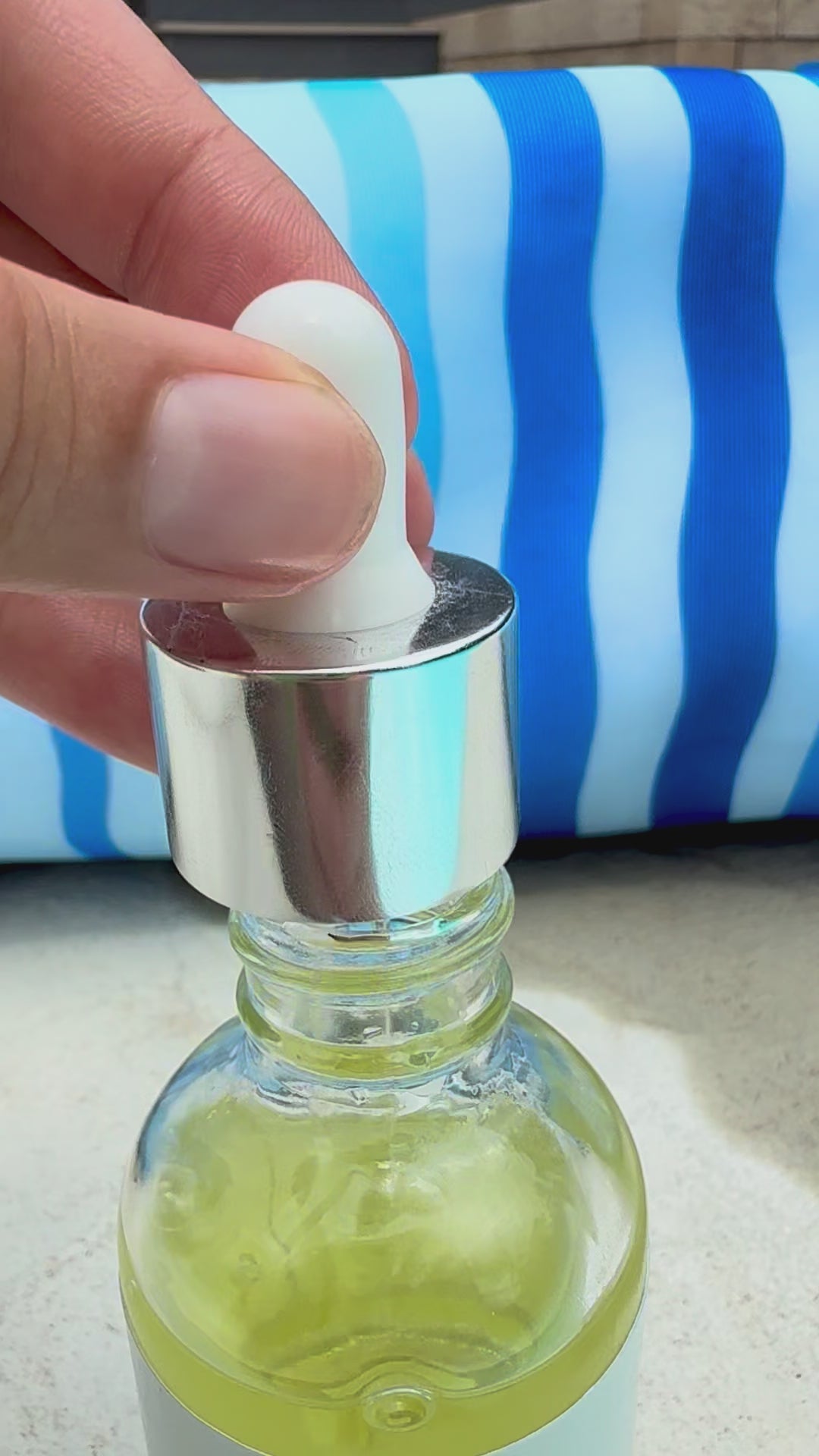 Lightweight skin revival body oil being dispensed from a dropper into the bottle