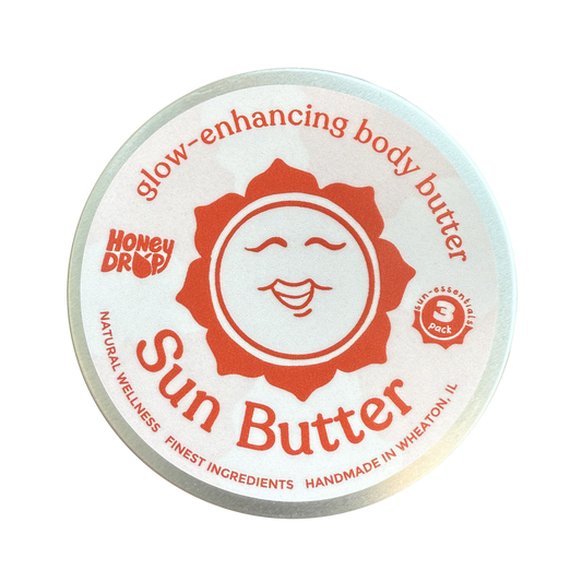 A round metal tin of HoneyDrop Sun Butter body butter, featuring a white lid with a prominent orange sun graphic and red text, isolated on a white background.